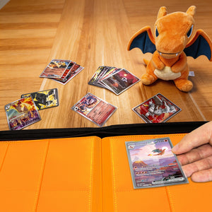 Hand placing a sleeved Pokemon card into an orange 9-pocket page beside a Charizard plush on a wood table