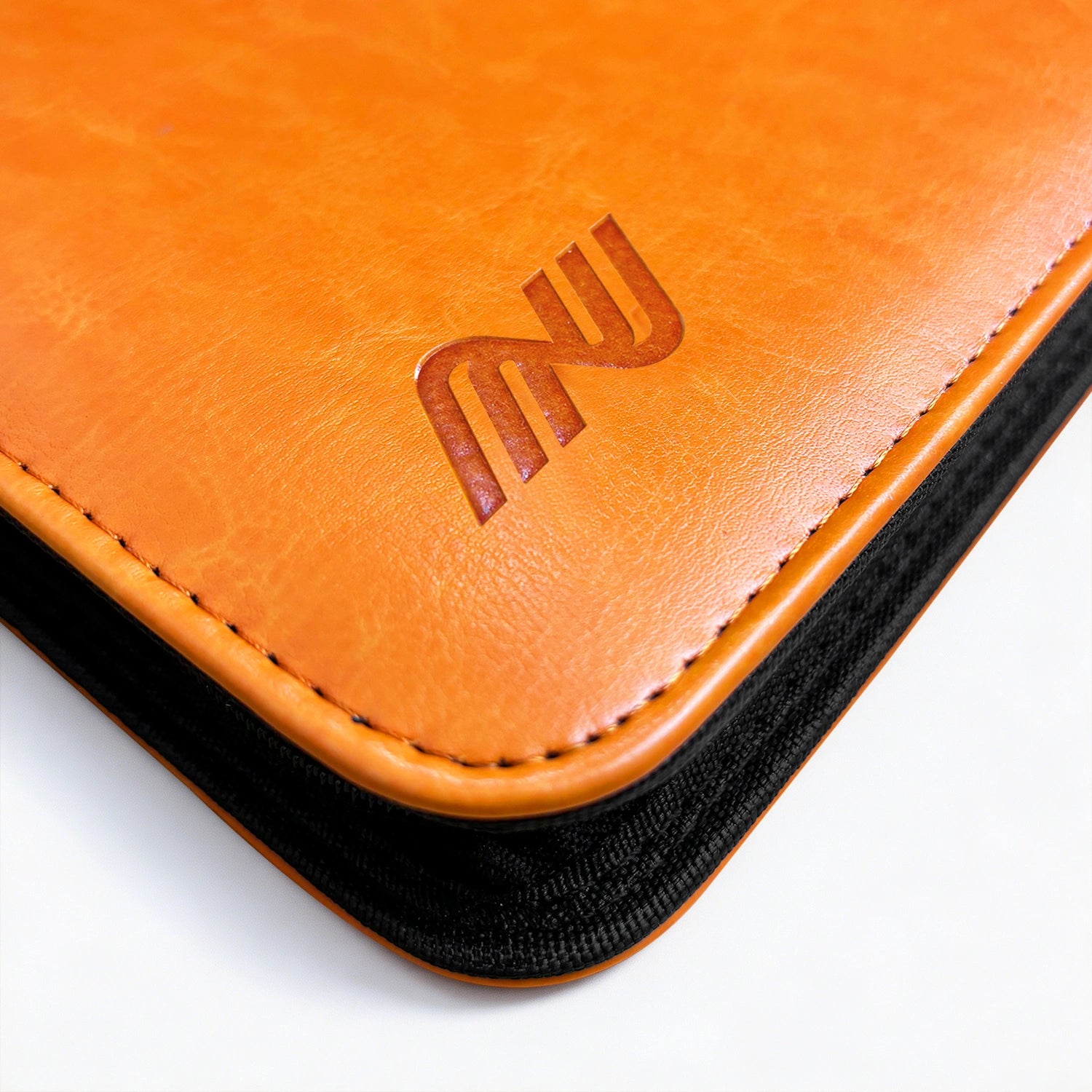 Close-up of the embossed logo and stitching on an orange leather Pokemon card binder corner