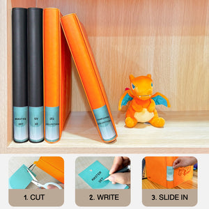 Orange and black Pokemon toploader binders lined up on a shelf with customizable spine labels beside a Charizard plush
