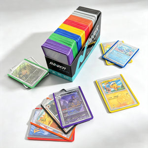Open box of color-sorted toploaders on a desk with trading cards laid out in purple, yellow, blue and red edge toploaders