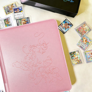 Pink Eevee Family toploader binder with debossed Pokemon line art, surrounded by cards in toploaders beside a black gift box