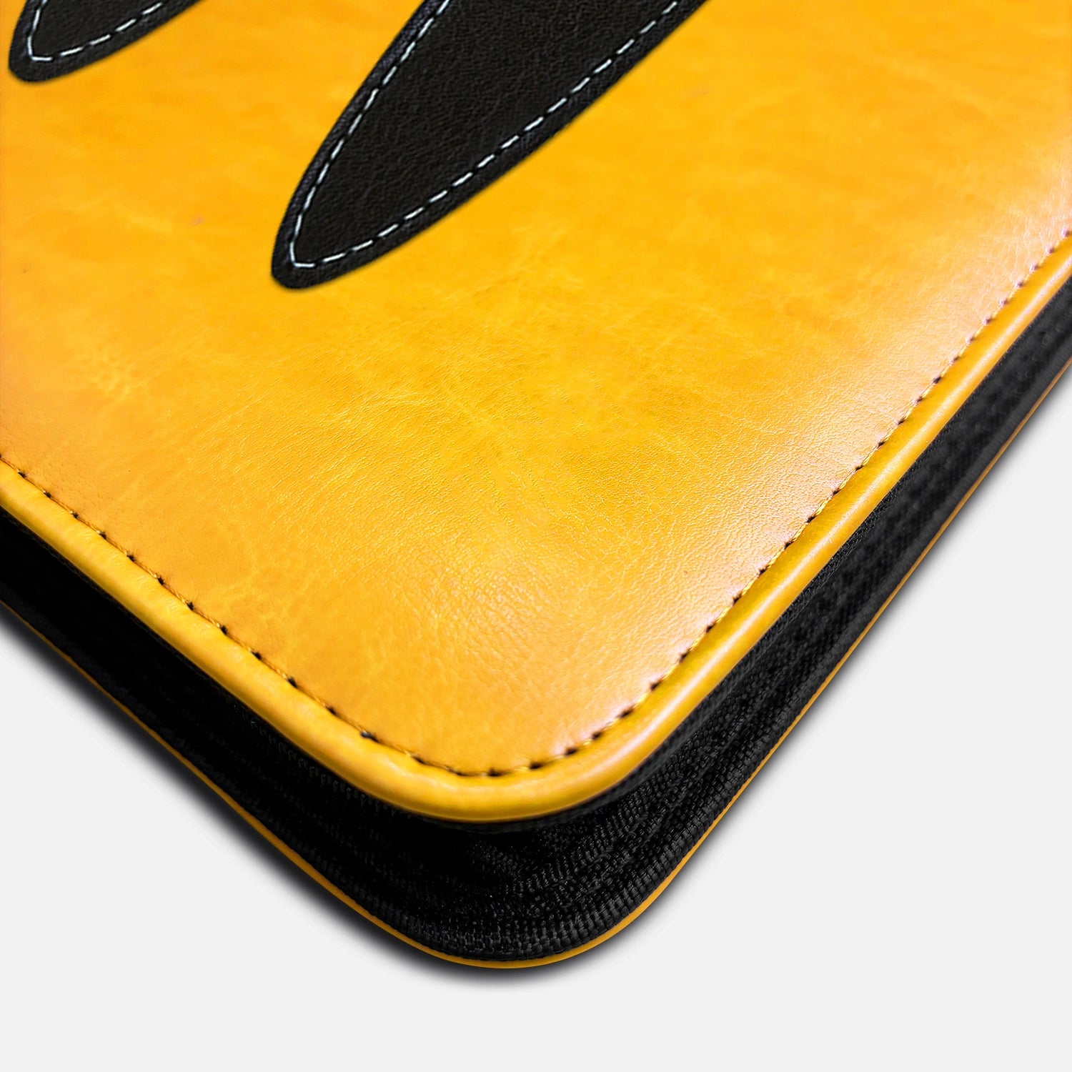 Close-up of the stitched black Pikachu ear tip and edge stitching on a yellow leather card binder corner