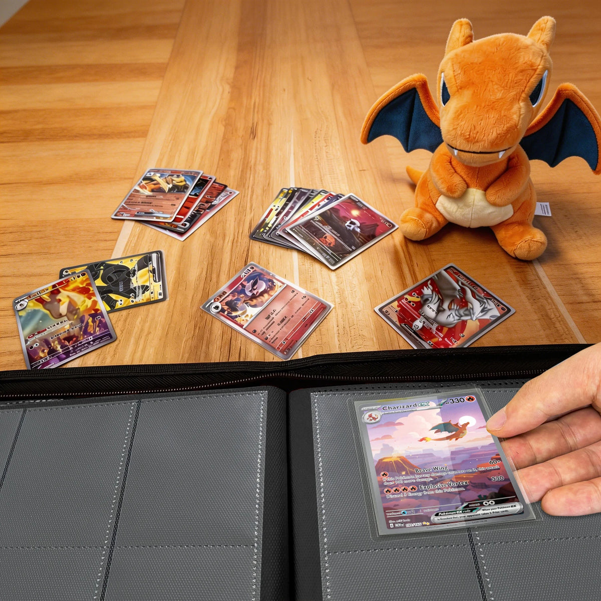 Hand placing a Pokemon card into a black 9-pocket binder on a wood table